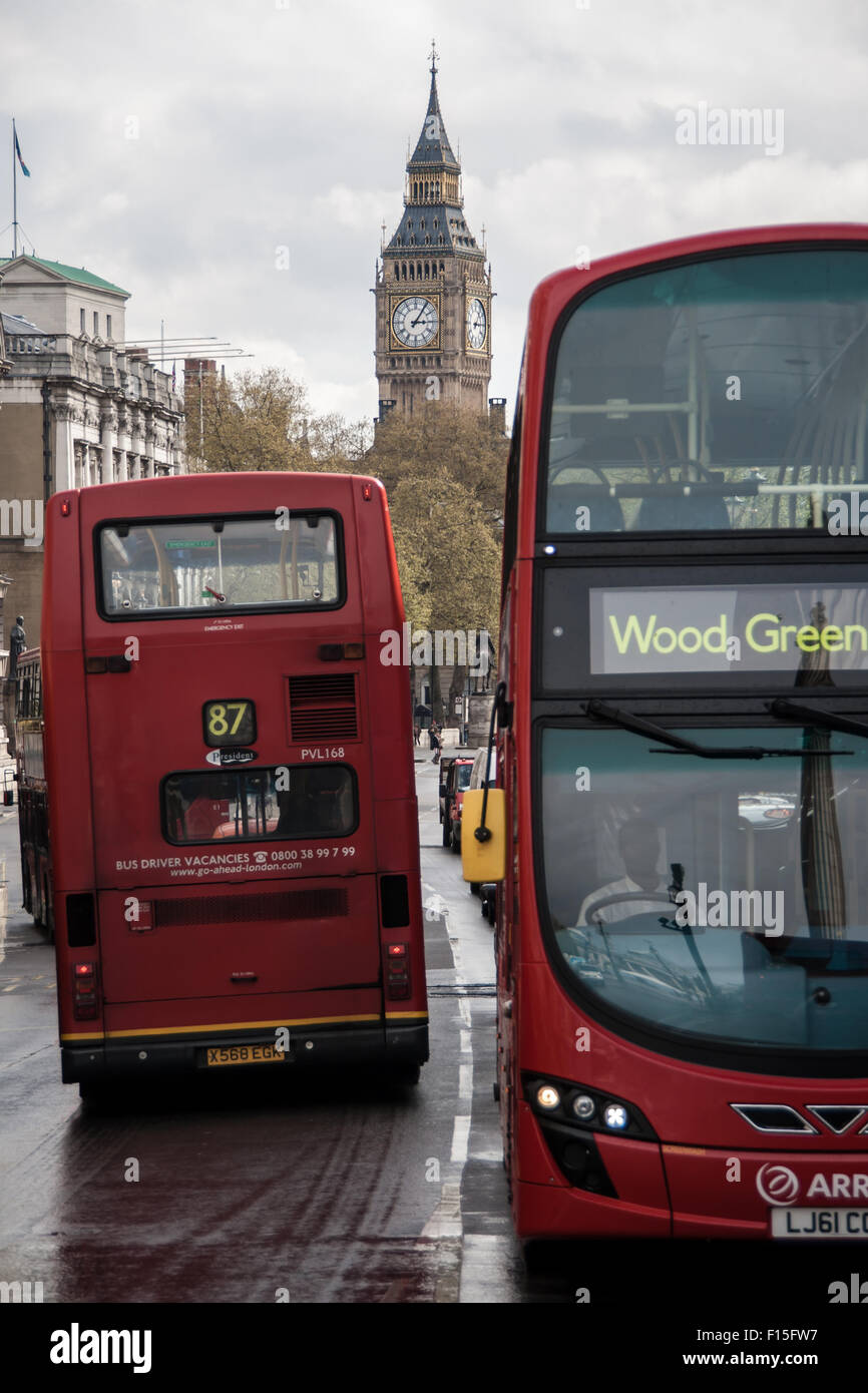 Scène de rue à Londres. Deux bus passant par et le Big Ben en arrière-plan. Banque D'Images
