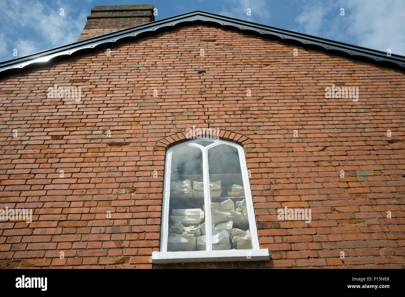 Articles empilés dans la fenêtre d'une entreprise à Saxmundham, Suffolk, UK. Banque D'Images