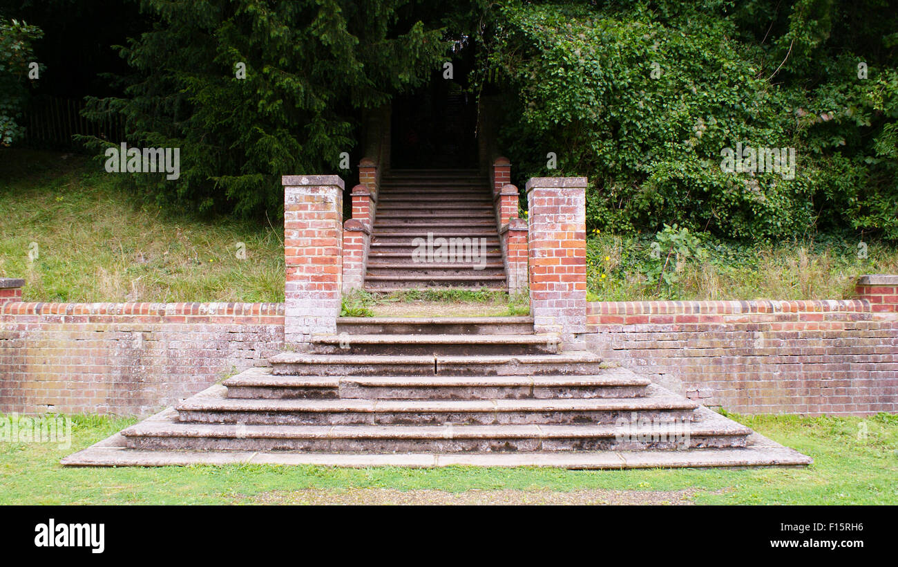 Coup d'escaliers symétriques dans un parc avec un brickwall et couverte d'arbres Banque D'Images