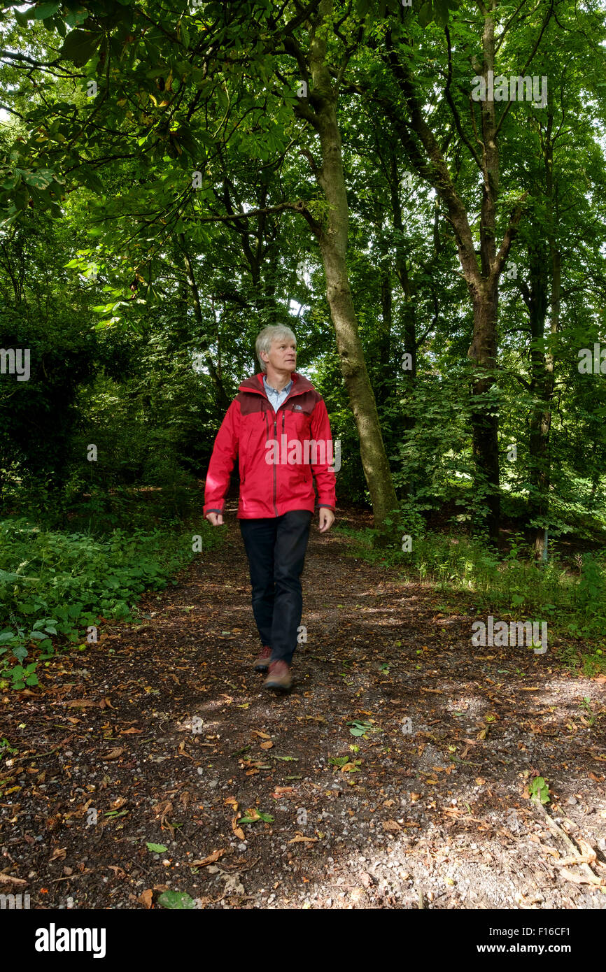 L'homme en rouge veste de plein air randonnée pédestre vers la caméra le long chemin forestiers Banque D'Images