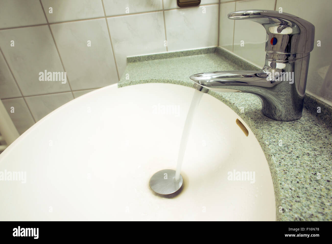 Ouvrez un robinet d'eau au lavabo en céramique blanche Banque D'Images