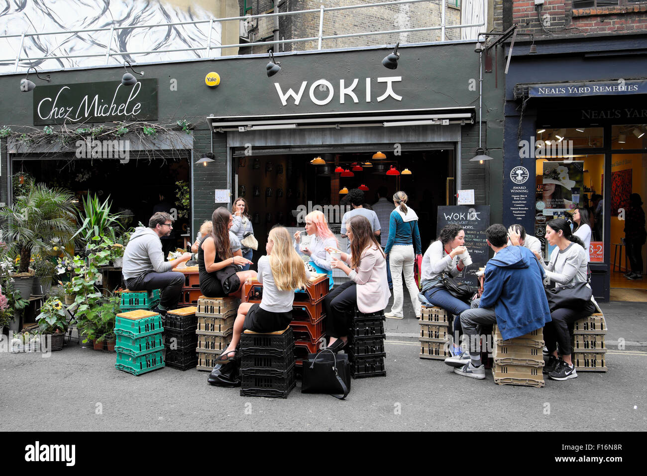 Les jeunes boire et manger assis sur des caisses à l'extérieur de WOKIT restaurant le midi en été près de Borough Market, dans le sud de Londres UK KATHY DEWITT Banque D'Images