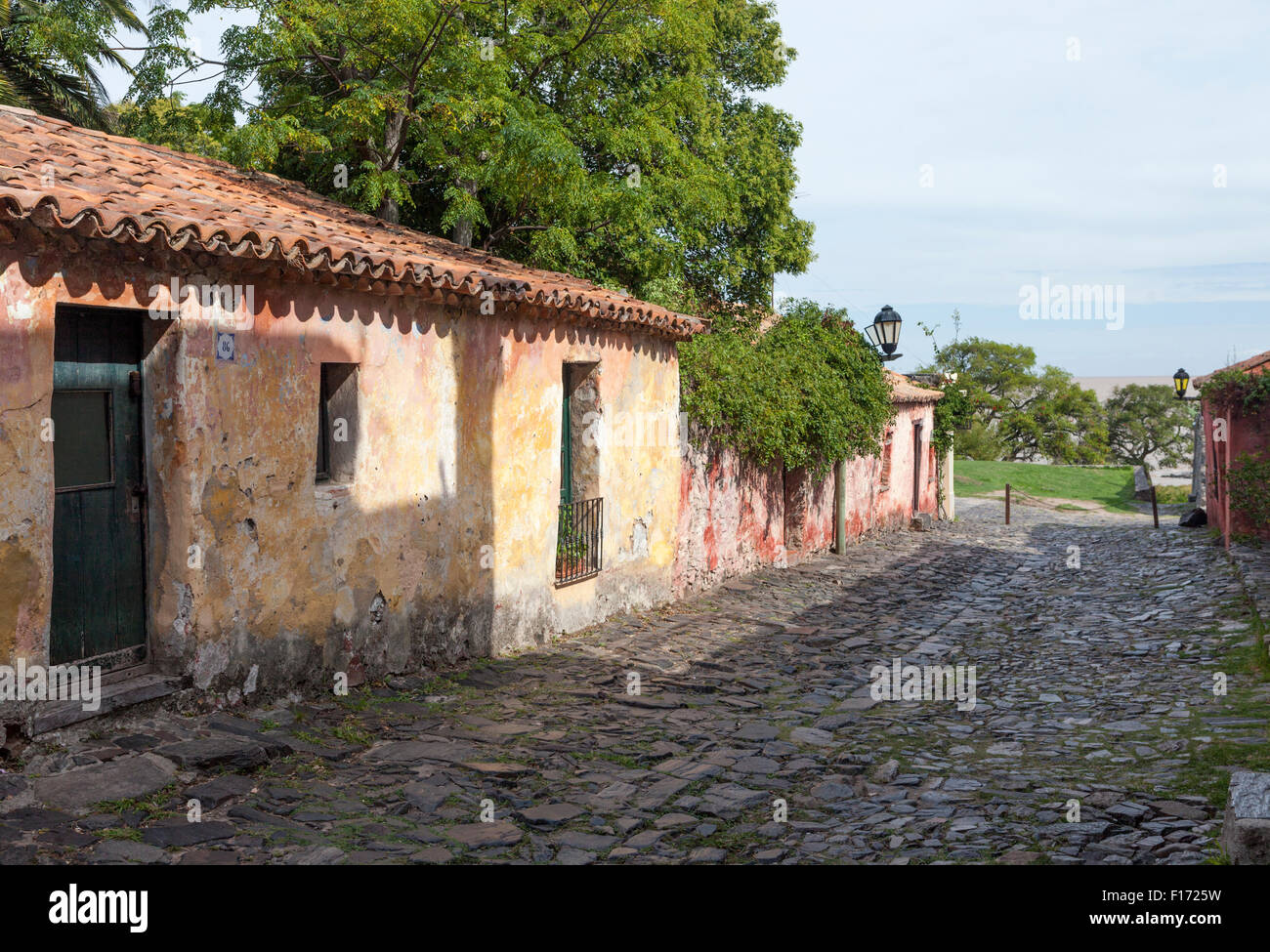 Cottages au toit de tuiles rouges sur stuc pierre pavée à Colonia del Sacramento, Uruguay. Le River Plate est visible au-delà. Banque D'Images