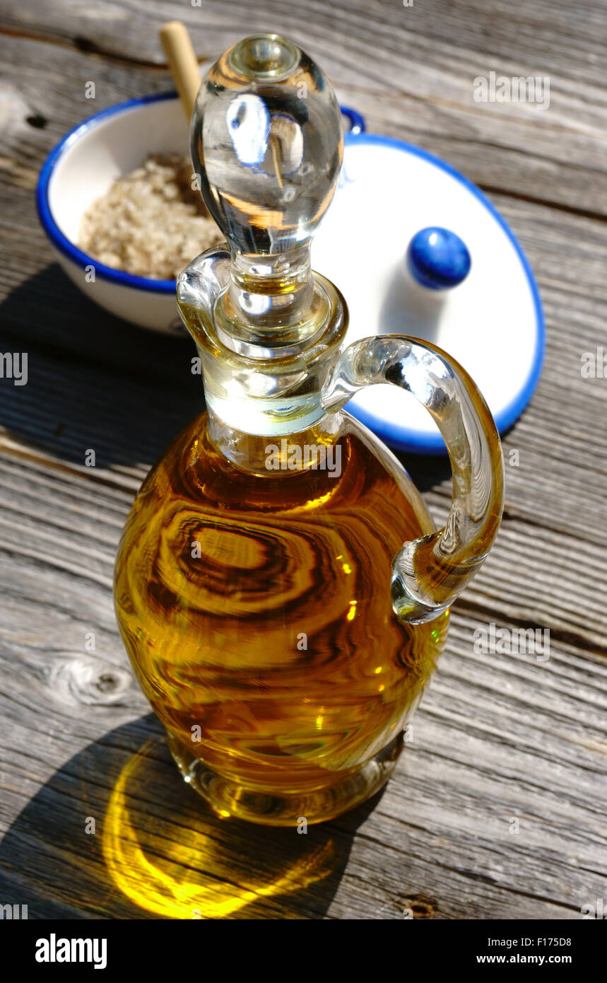 Carafe en verre avec de l'huile d'olive et un bol en porcelaine de fleur de sel sel sur table en bois rustique Banque D'Images