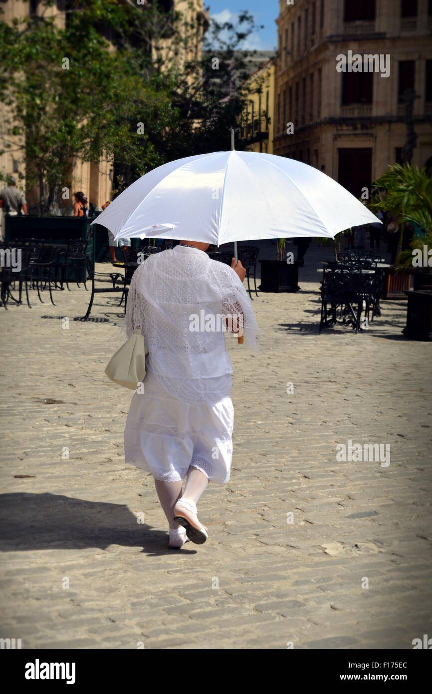 Santera cubain, dame en blanc tous marcher dans la Vieille Havane, à l'aide  d'un parapluie blanc à l'ombre d'elle-même le soleil de midi Photo Stock -  Alamy