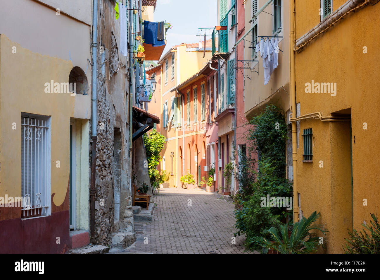 Sunny rue étroite avec des vieux bâtiments et des plantes en pot vert en ville médiévale Villefranche-sur-Mer sur la côte d'Azur, Banque D'Images