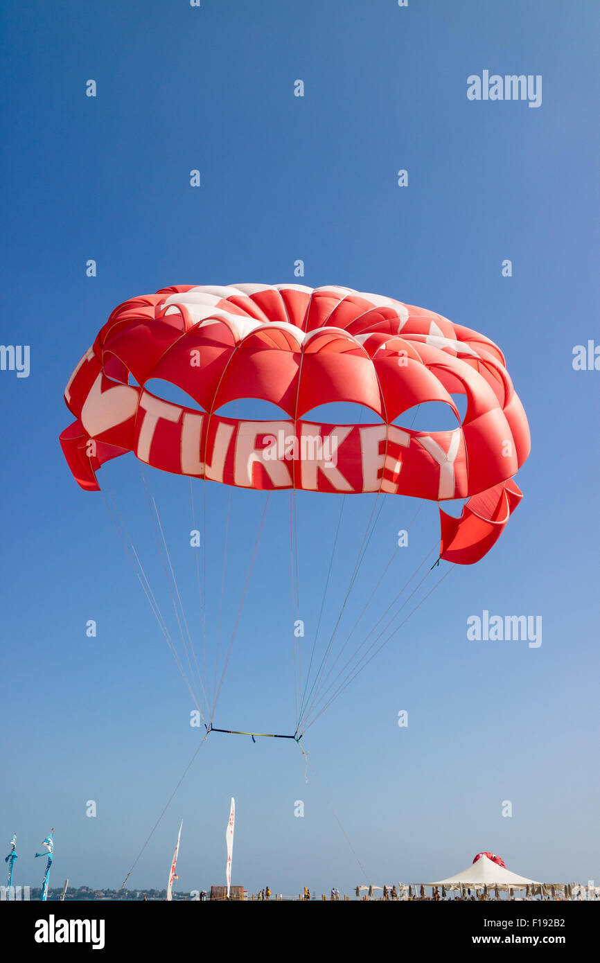Un parachute rouge avec 'J'aime la Turquie" écrit sur elle vole d'une plage en Turquie sous un ciel bleu clair Banque D'Images