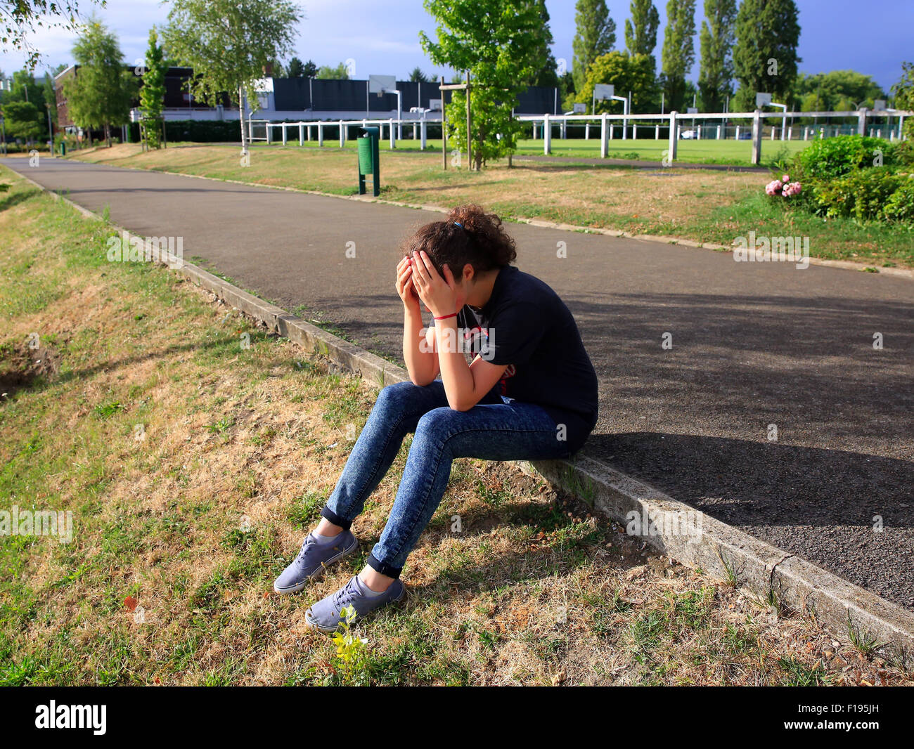 Upset girl sitting dans la cour de l'école Banque D'Images