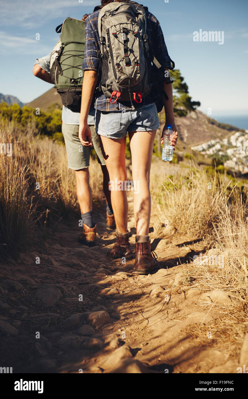 Vue arrière du jeune couple trekking ensemble dans la campagne. Randonneur couple walking through sentier sur la montagne. Randonnées dans la nature. Banque D'Images