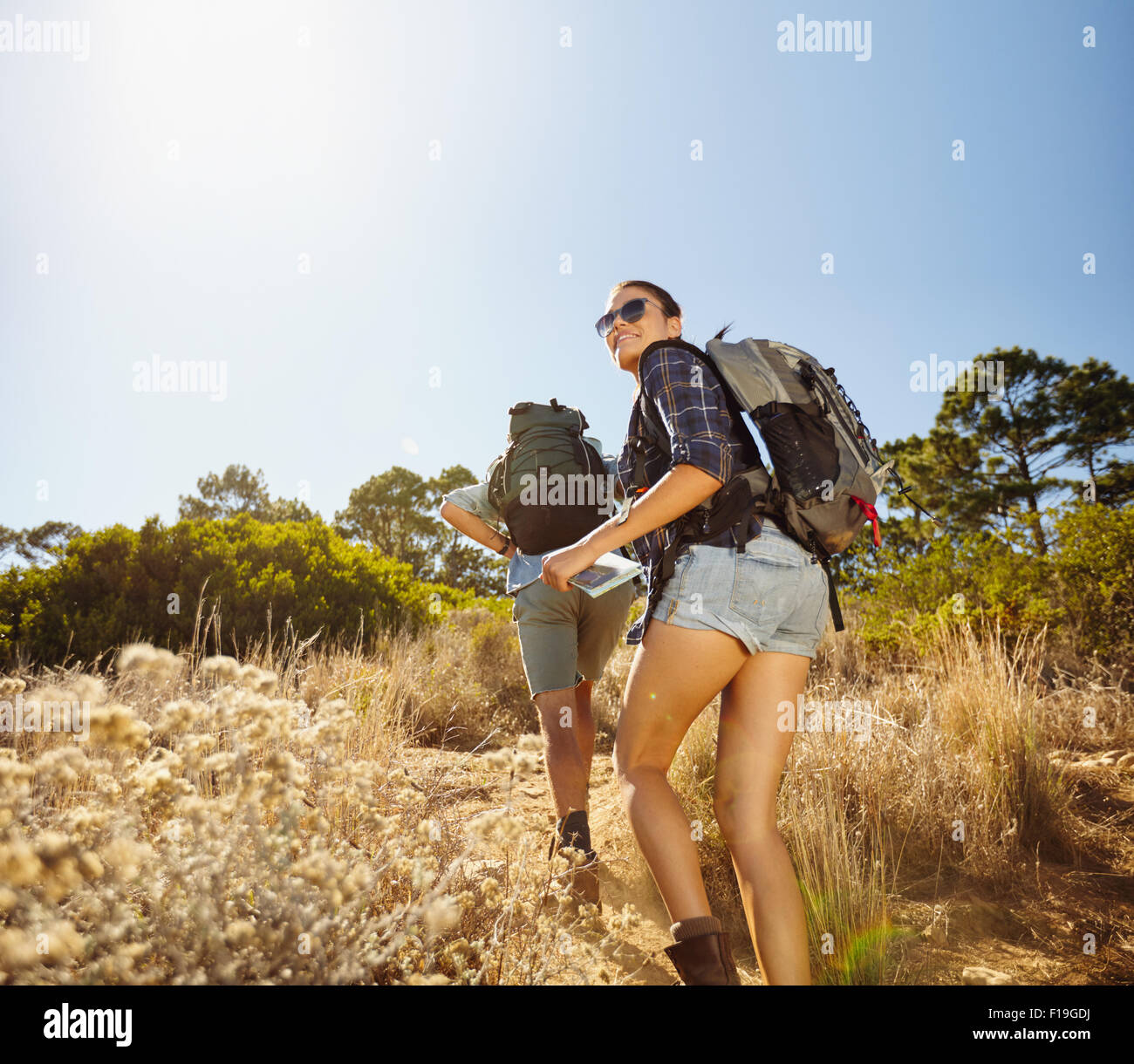 Des jeunes faisant une montée lors d'une randonnée dans la campagne environnante. Femme avec la carte la recherche en arrière sur son épaule en souriant avec man wa Banque D'Images