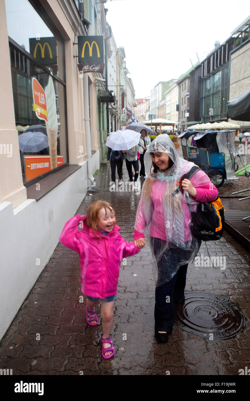Mère et fille marcher main dans la main et se mettre à l'eau sous la pluie dans les rues de Tallinn Estonie Banque D'Images
