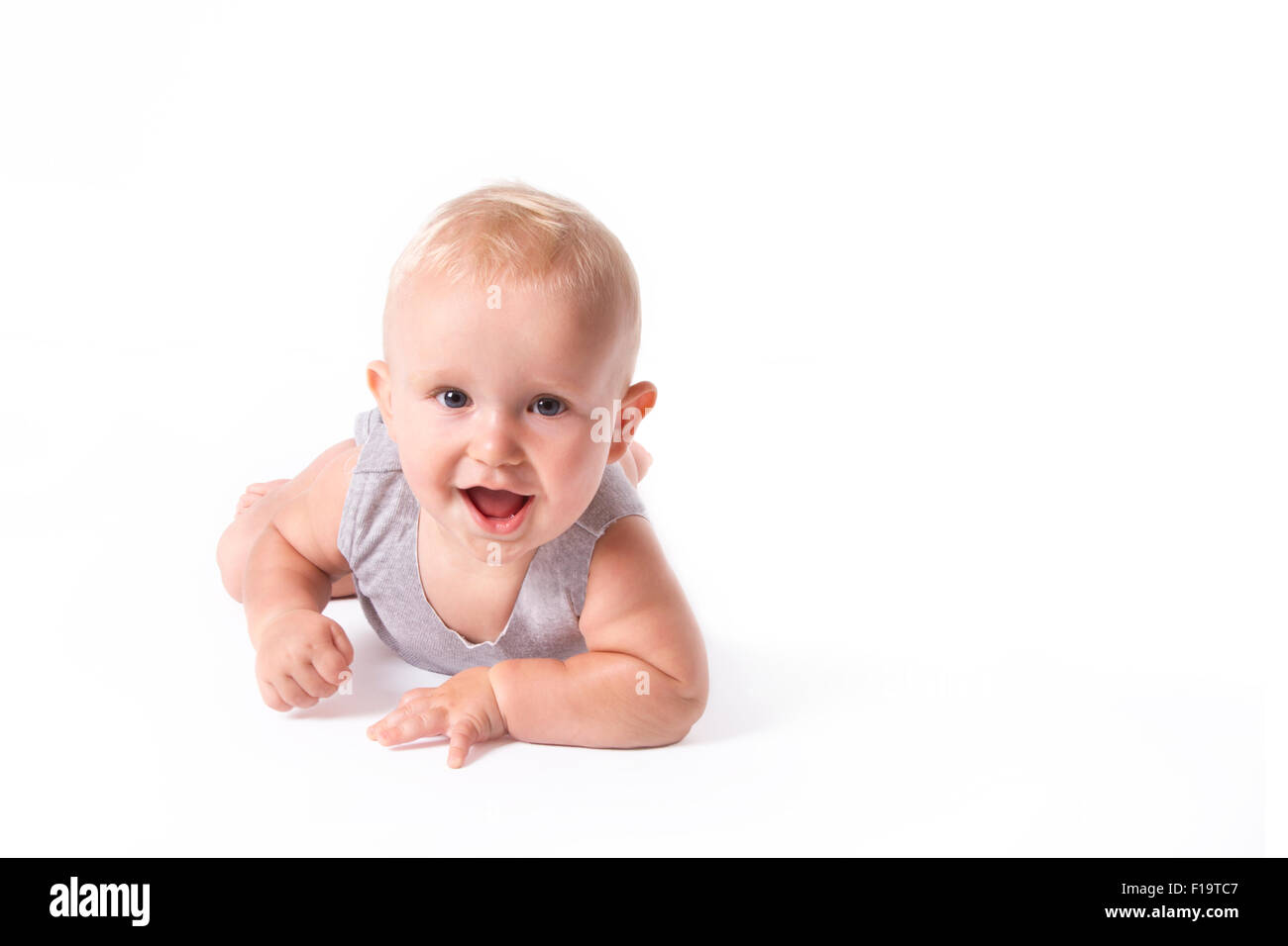 Studio shot of baby boy jouant sur le sol à la recherche de l'appareil photo. Banque D'Images