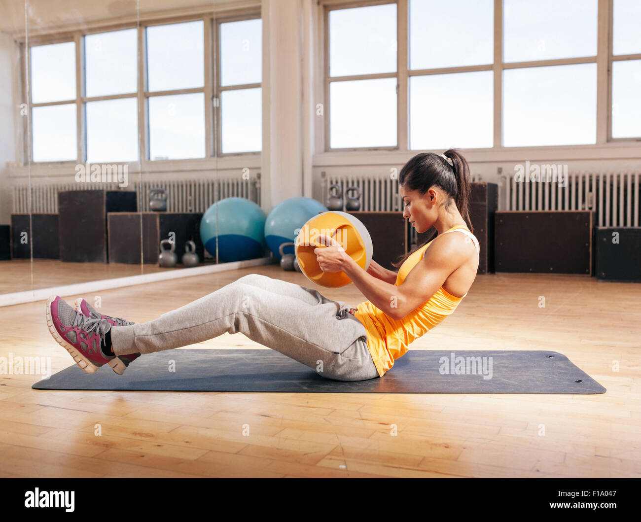 Vue de côté tourné de la jeune femme à l'aide d'entraînement Crossfit kettlebell. Modèle de remise en forme de l'exercice dans la salle de sport. Banque D'Images