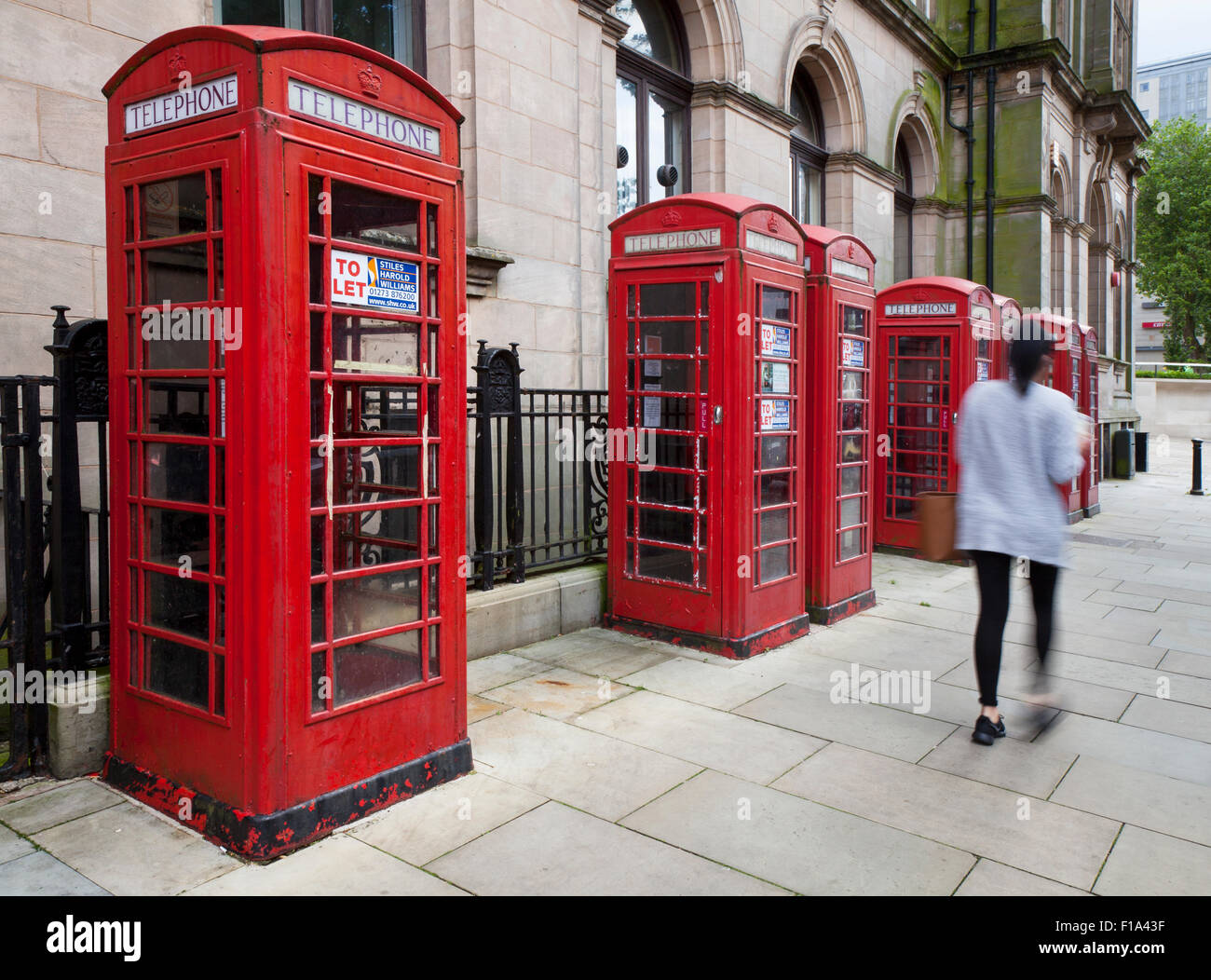 Les personnes de passage K6 Ancien type GPO, ou des cabines téléphoniques rouges BT commercialisées comme étant 'à laisser' avec diverses utilisations suggérées par l'agent. Preston, Royaume-Uni Banque D'Images