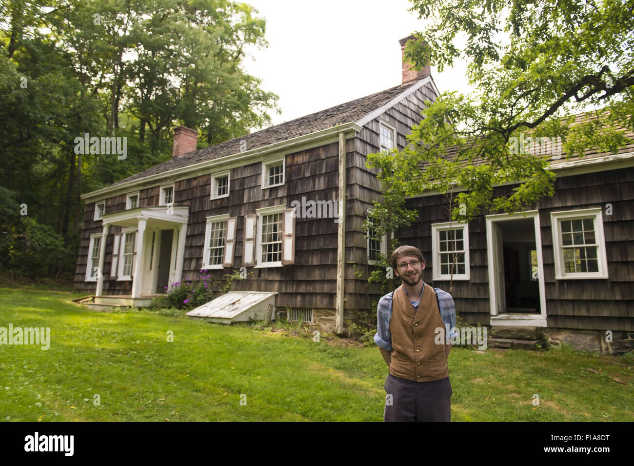 Old Bethpage, New York, USA. Août 30, 2015. Matt, un membre du personnel saisonnier portant des vêtements américains de style traditionnel, se situe à l'avant de la Powell House à la fin d'une tournée au cours de l'Old Time Music Week-end à Old Bethpage Village Restauration. La maison a été construite en 1750 et est restauré à sa taille, et élargi 1855 est le seul immeuble de standing sur son emplacement d'origine dans le village. Credit : Ann Parry/ZUMA/Alamy Fil Live News Banque D'Images