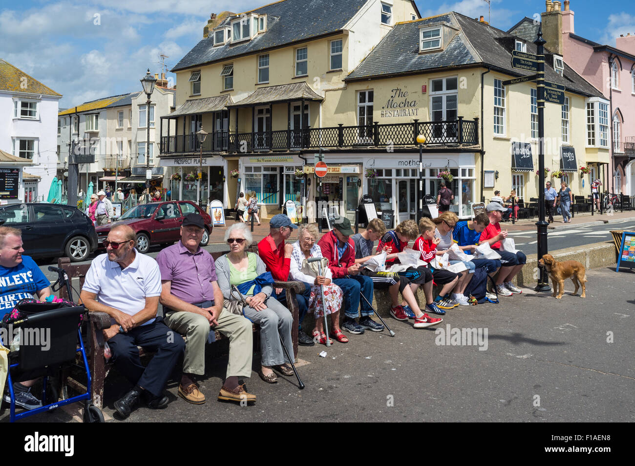 La ville de Sidmouth, Devon. 2015. Un groupe de retraités sont assis le long du front de mer de Sidmouth avec la ville en arrière-plan. Banque D'Images