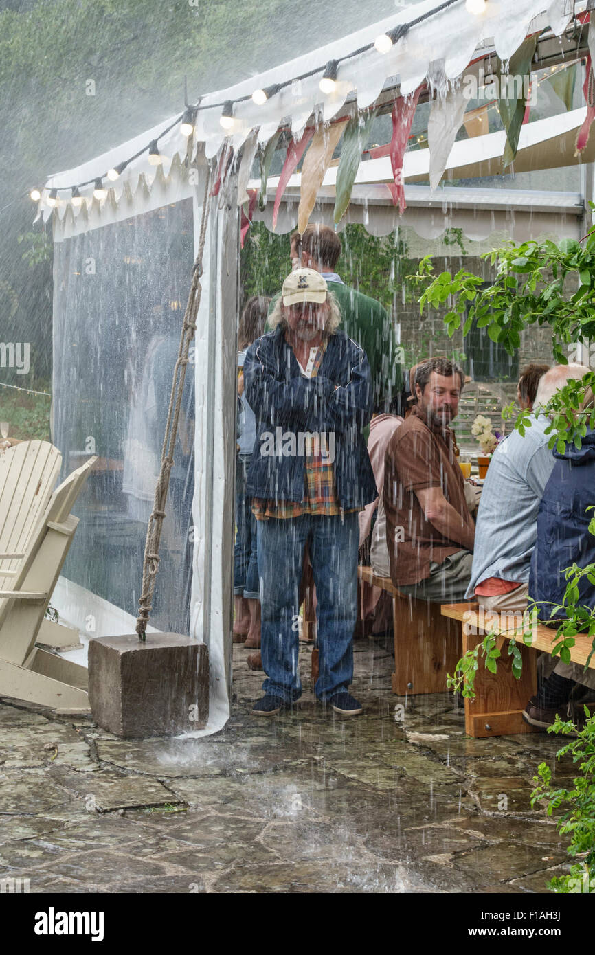 Pays de Galles, Royaume-Uni. S'abritant sous un chapiteau pendant une averse à une garden-party à l'été pluvieux de 2015 Banque D'Images