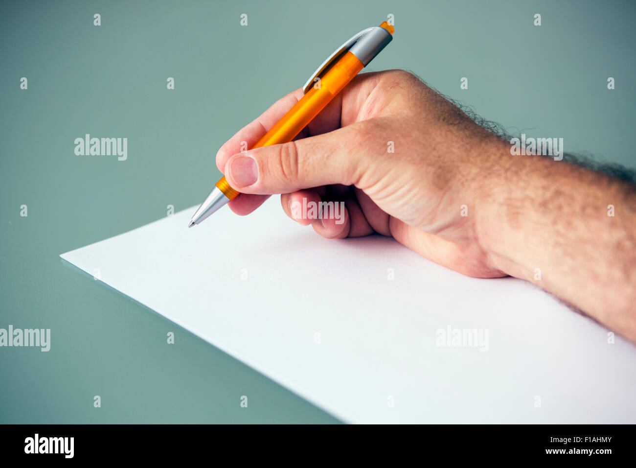 Libre de la main d'un homme tenant un stylo et une feuille de papier blanc sur la table Banque D'Images