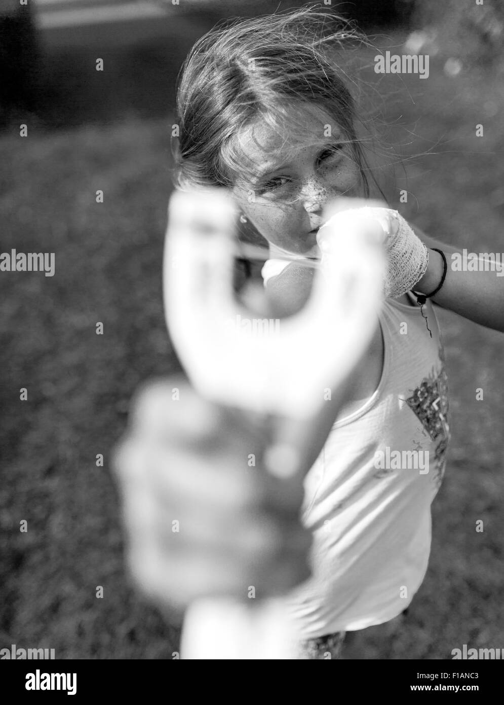 Fille avec slingshot pointing at viewer Banque D'Images