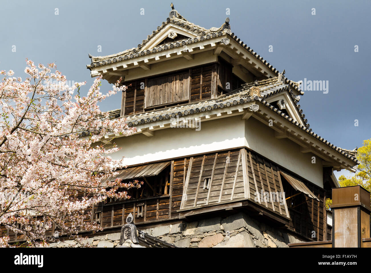 Le Japon, Château Kumamoto. Le Hohoate avec tourelle porte chute pierre trou, fleur de cerisier d'un côté, et de gros nuages sombres comme arrière-plan. Banque D'Images