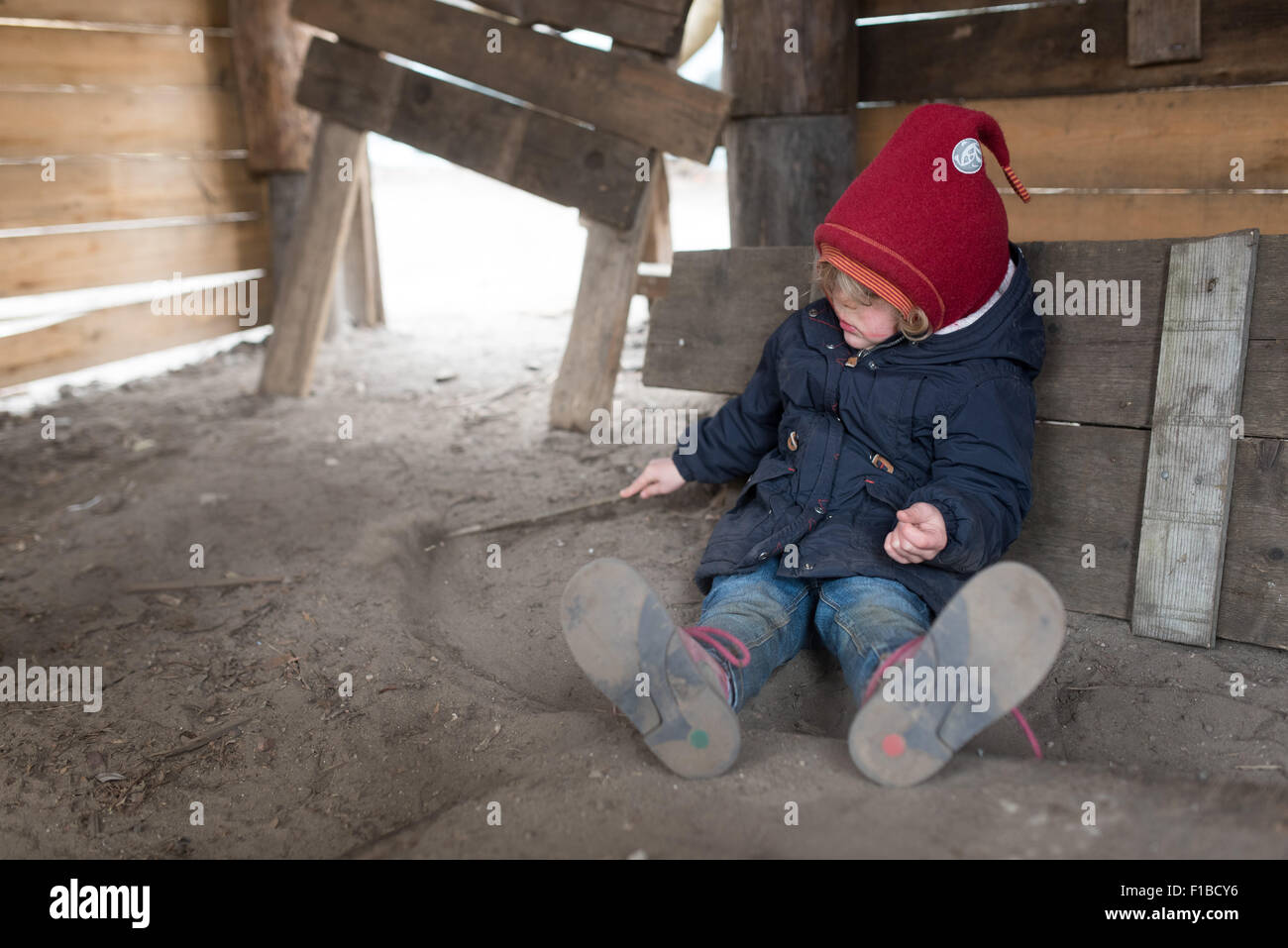 Petite fille jouant avec un bâton dans le sable à une aire de jeux Banque D'Images