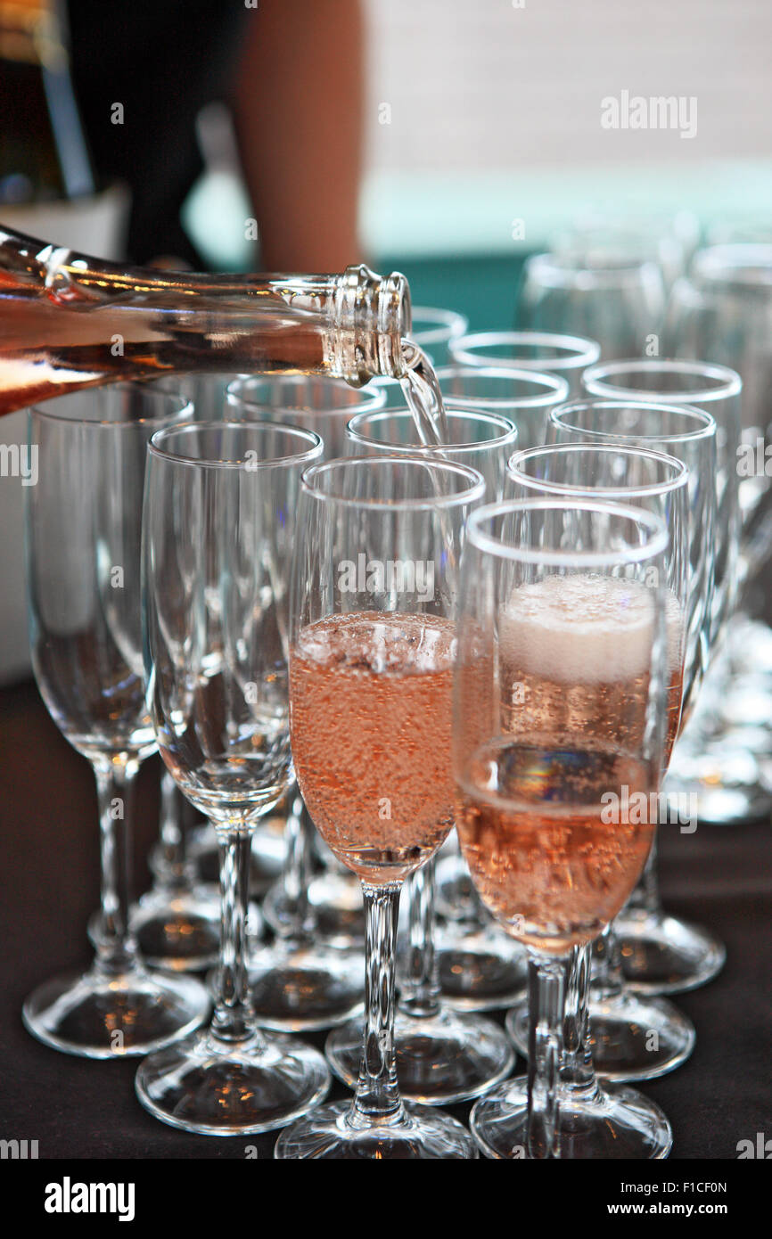 Champagne rose est versé dans les verres de champagne Banque D'Images