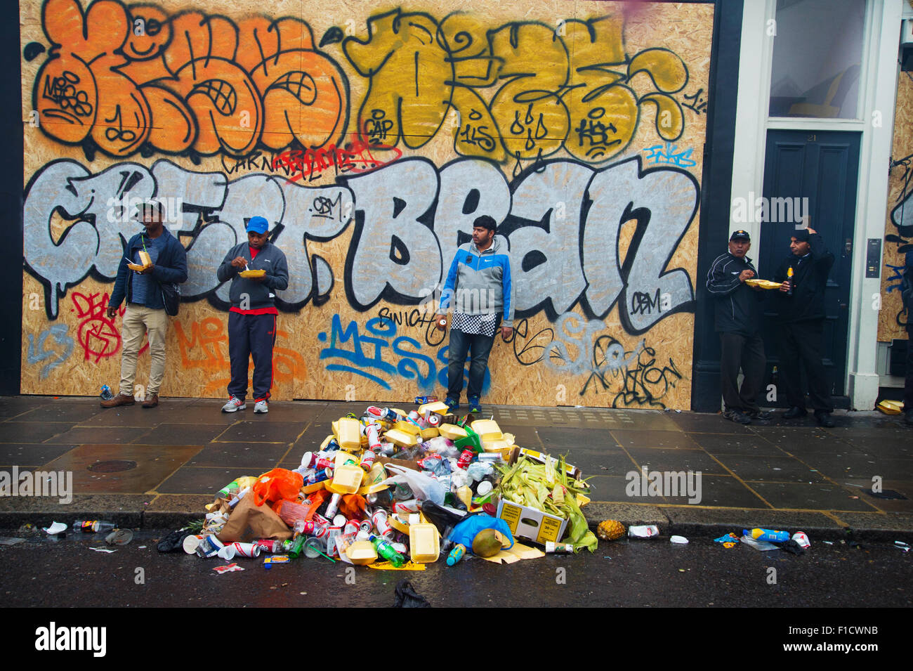 Notting Hill Carnival 2015. Tas de détritus dans la pluie en face de mur peint. La mise à l'abri les gens mangent à retenir. Banque D'Images