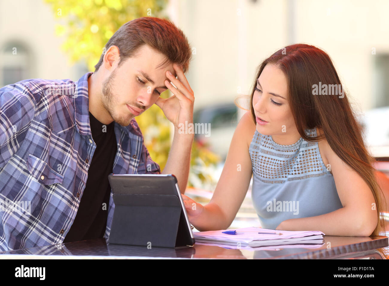 Deux inquiet frustré étudiant étranger et l'apprentissage avec un ami à lui et à l'aide d'une tablette Banque D'Images