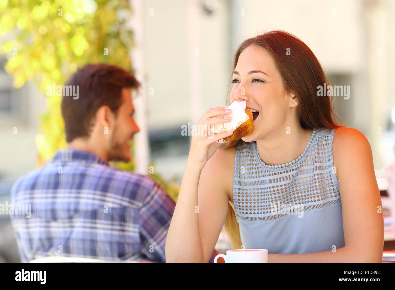 Happy woman eating a cupcake dans un café terrasse Banque D'Images