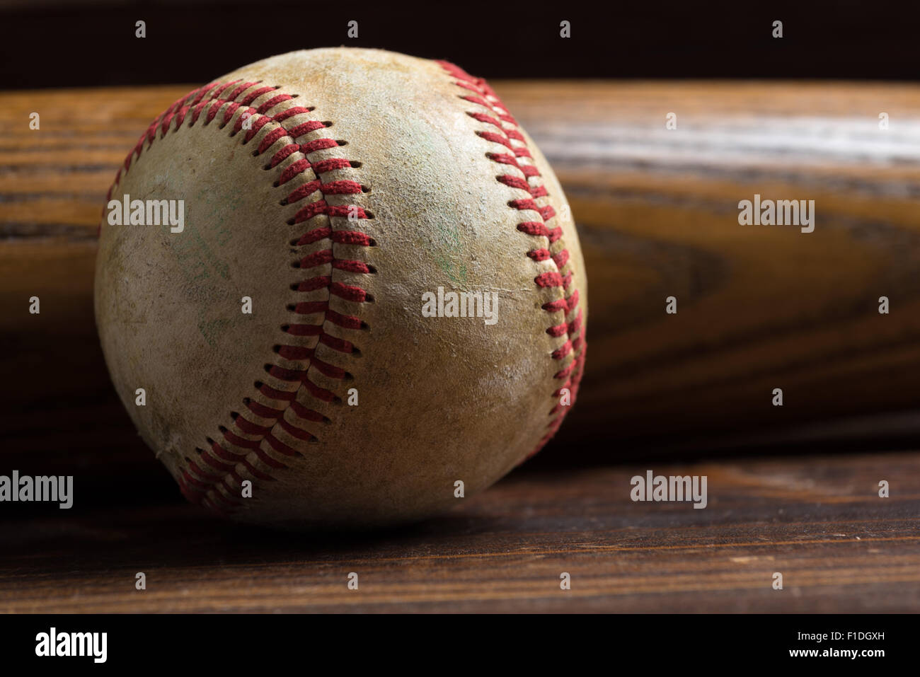 L'équipement de base-ball : batte en bois et balle sur une planche en bois ou un banc arrière-plan Banque D'Images