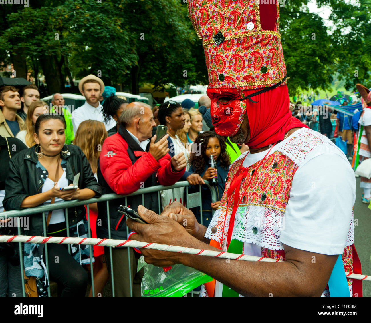 Leeds, West Yorkshire, Royaume-Uni. 31 août, 2015. L'attente sous la pluie pour le défilé du carnaval pour commencer, un parader envoie un texte de dernière minute, dans Potternewton ParkLeeds, West Yorkshire UK Crédit : Graham Hardy/Alamy Live News Banque D'Images