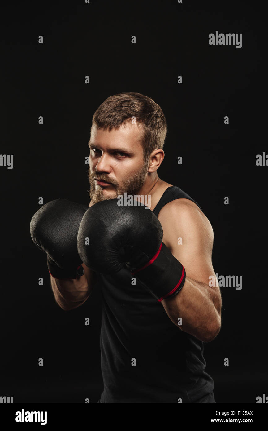 Athletic boxer barbu avec des gants sur fond sombre Banque D'Images