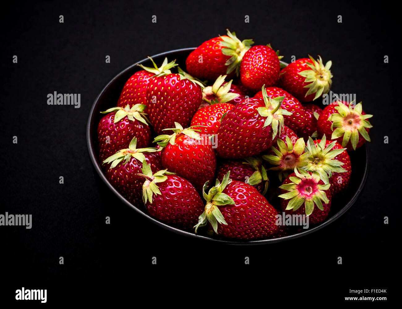 Dans un bol de fraises fraîches mûres sur fond noir, vue du dessus Banque D'Images