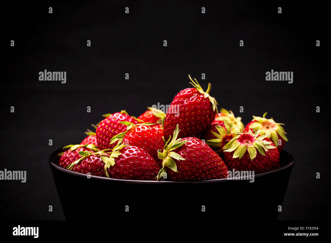 Dans un bol de fraises fraîches mûres sur fond noir, Close up Banque D'Images