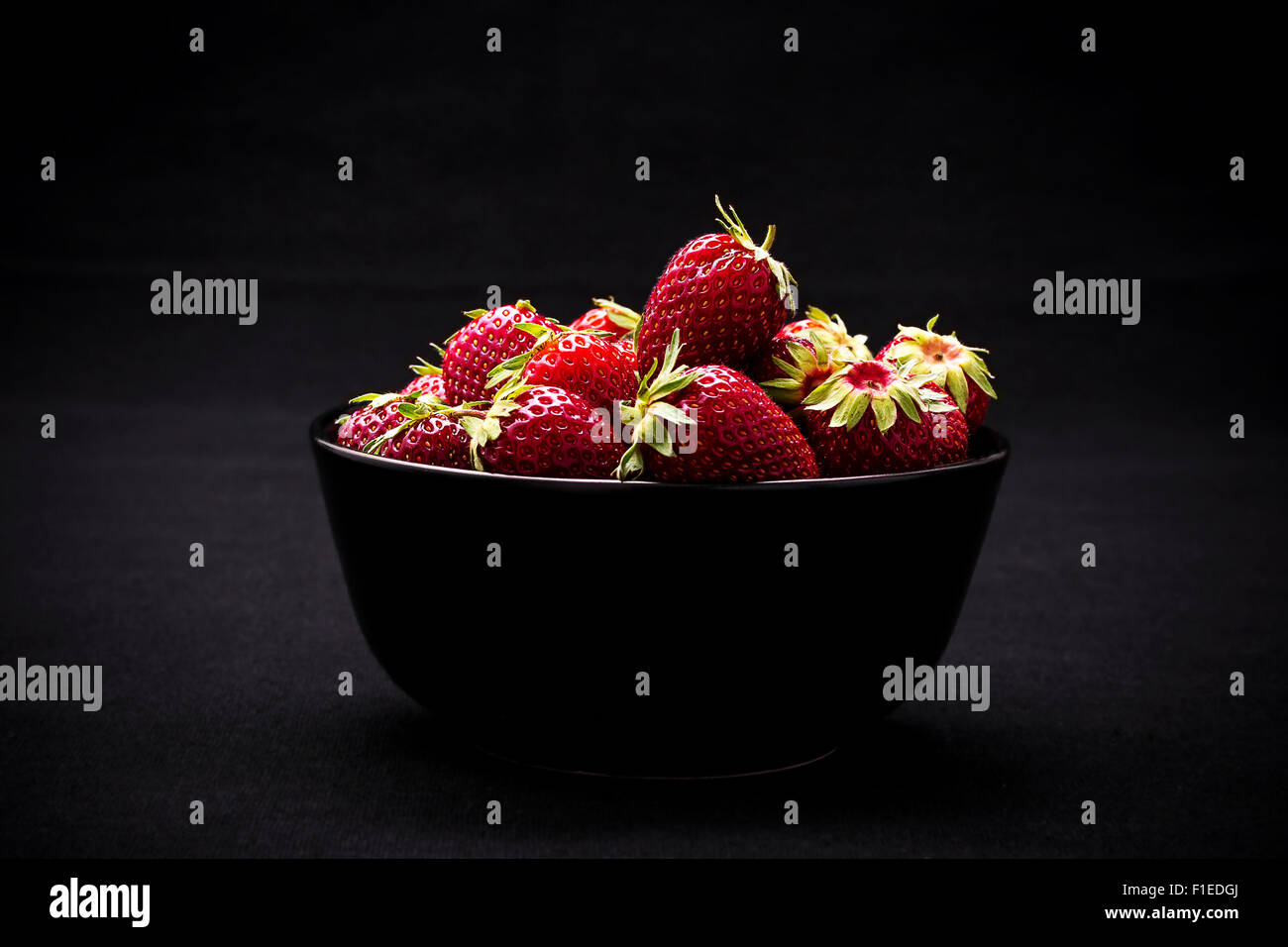 Dans un bol de fraises fraîches mûres sur fond noir Banque D'Images