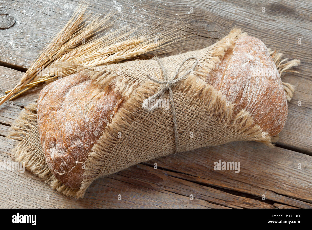 Du pain frais et les épis de blé sur la vieille table en bois. Banque D'Images