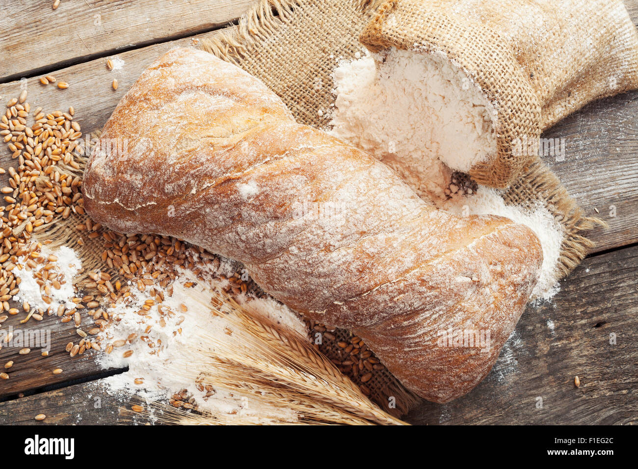 Du pain frais, sac de farine et les épis de blé sur une table en bois rustique. Banque D'Images