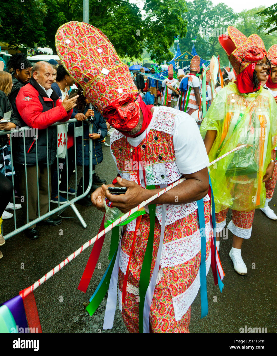 Leeds, UK. Août 31, 2015. L'attente sous la pluie pour le défilé du carnaval pour commencer, un parader envoie un texte de dernière minute, dans Potternewton ParkLeeds, West Yorkshire UK Crédit : Graham Hardy/Alamy Live News Banque D'Images