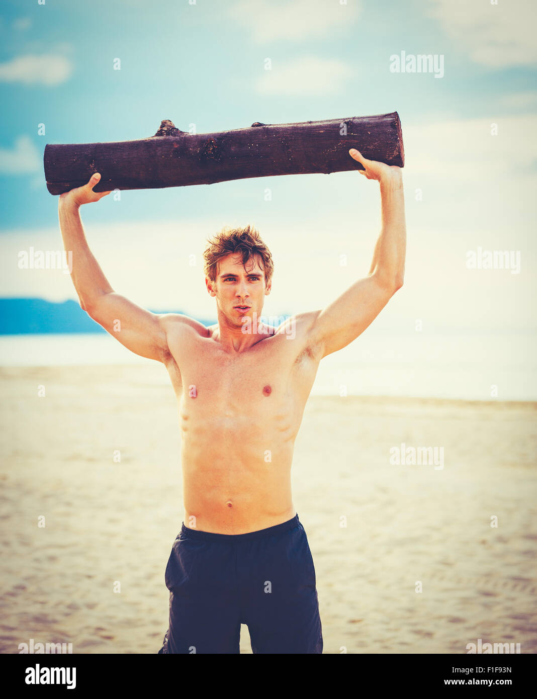 Plage de CrossFit entraînement. L'exercice de l'athlète masculin en plein air sur la plage avec tree log. Condition physique et mode de vie sain. Banque D'Images