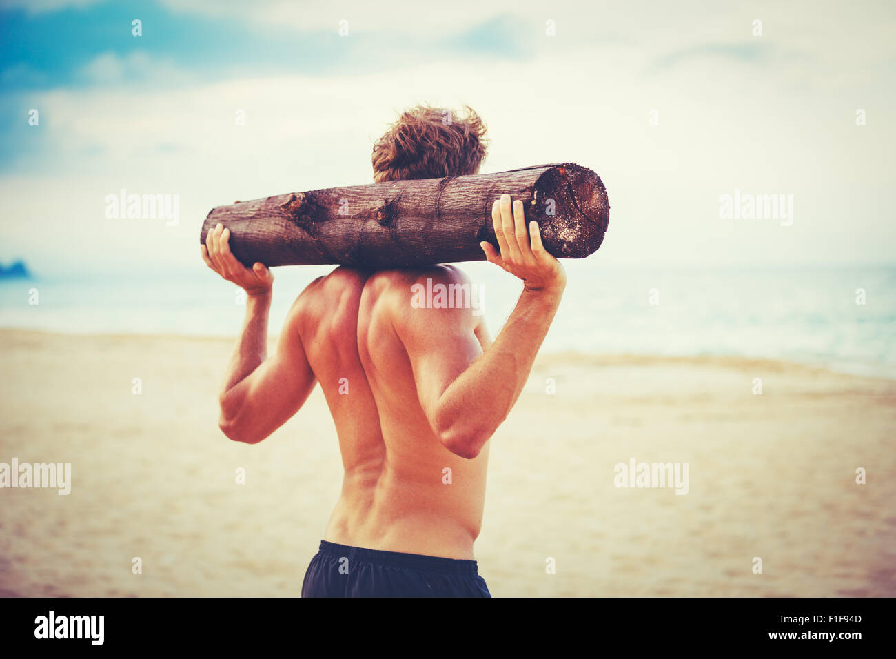 Plage de CrossFit entraînement. L'exercice de l'athlète masculin en plein air sur la plage avec tree log. Condition physique et mode de vie sain. Banque D'Images