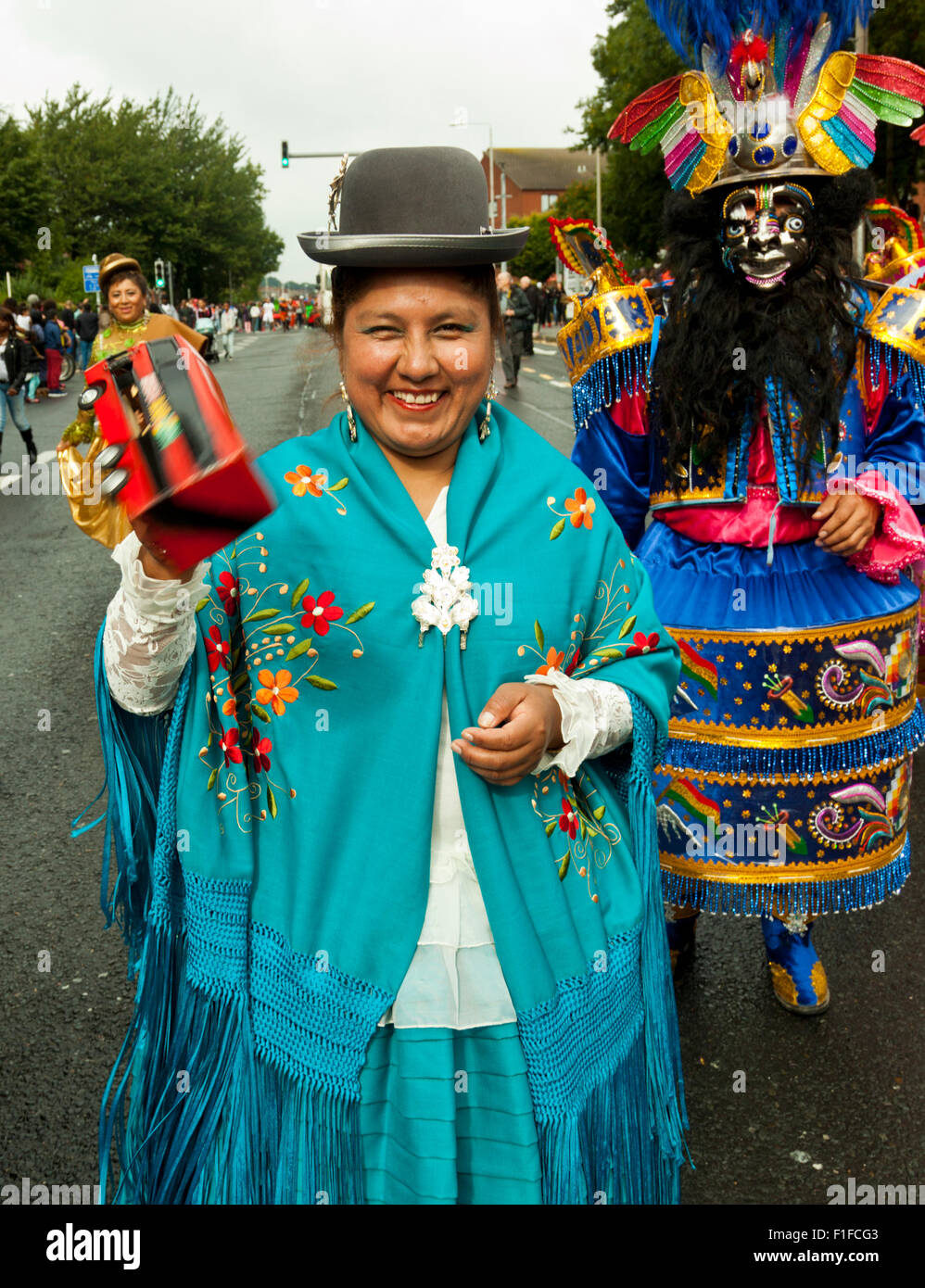 Leeds, UK. Août 31, 2015. Une femme vêtue d'un costume traditionnel carnaval bolivien, tenant un hochet bus, marcher le long de Roundhay Road pendant le défilé de carnaval Antillais de Leeds, West Yorkshire, UK Crédit : Graham Hardy/Alamy Live News Banque D'Images
