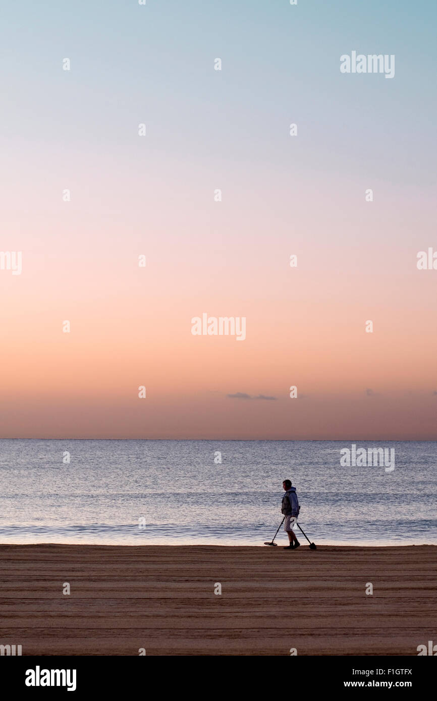 Homme seul avec un détecteur de métaux sur la plage de Saint Aygulf (France) au lever du soleil. Banque D'Images