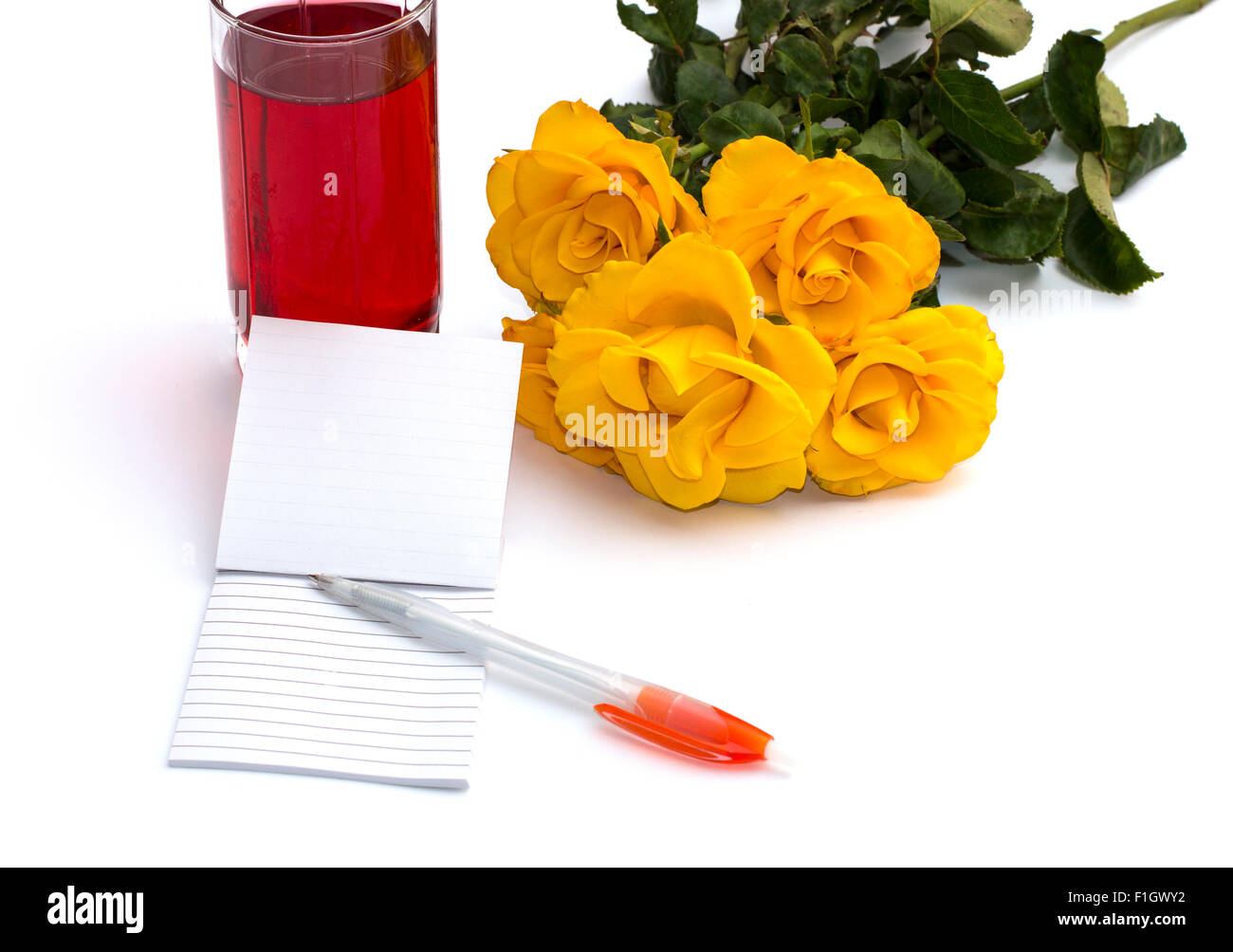 Verre de jus, ordinateur portable avec la poignée et un bouquet de roses Banque D'Images