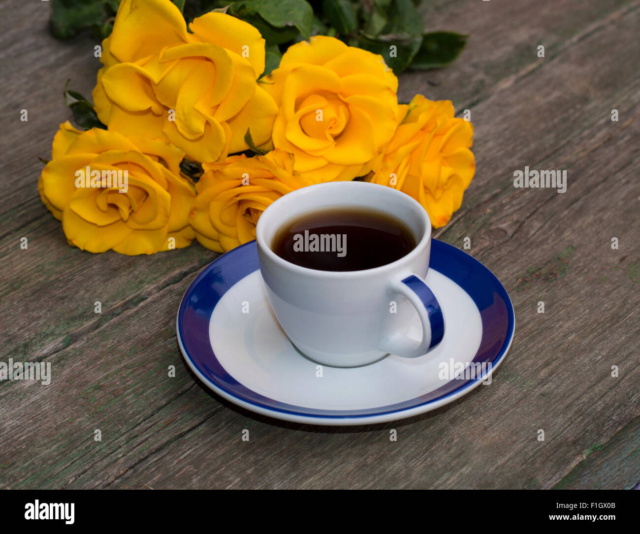 Tasse de café et fleurs jaunes sur une vieille table Banque D'Images