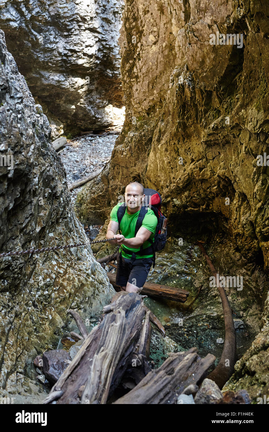 Caucasian hiker grimper sur une des chaînes de sécurité à travers un canyon très difficile Banque D'Images
