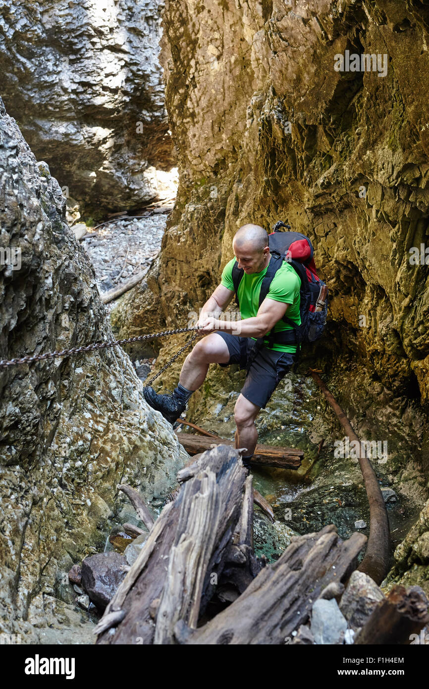 Caucasian hiker grimper sur une des chaînes de sécurité à travers un canyon très difficile Banque D'Images