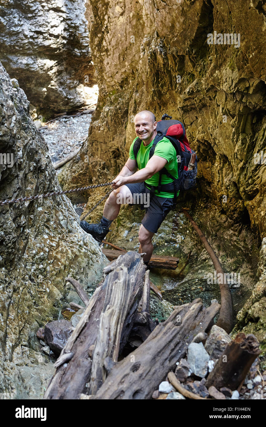 Caucasian hiker grimper sur une des chaînes de sécurité à travers un canyon très difficile Banque D'Images
