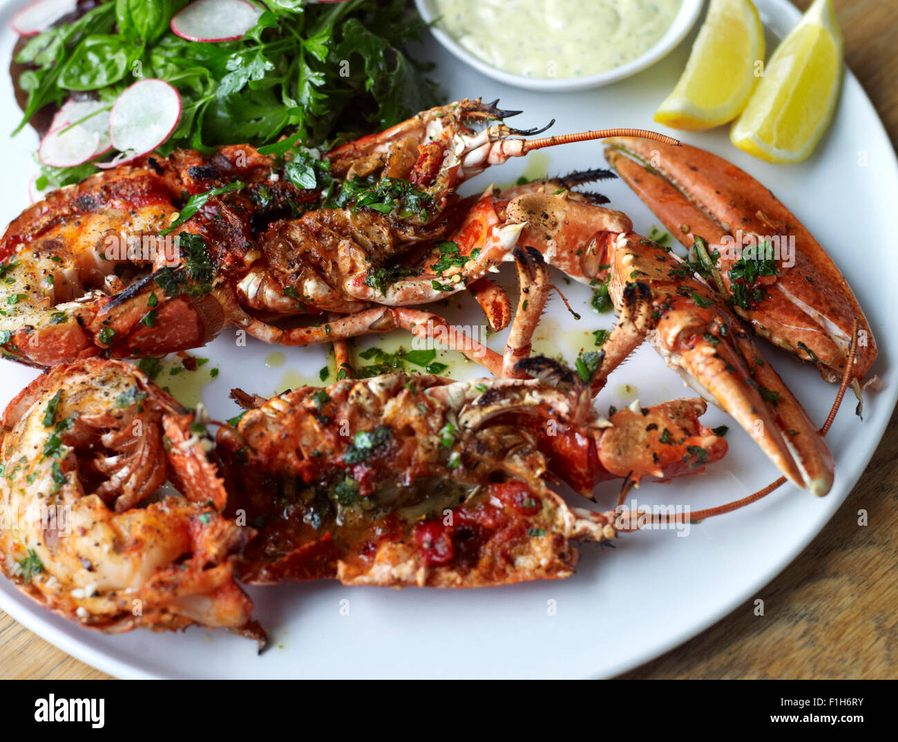 Un gros plan du homard et des crustacés présentés sur une assiette avec du citron, sauce tartare, assaisonnement, et une salade. Banque D'Images