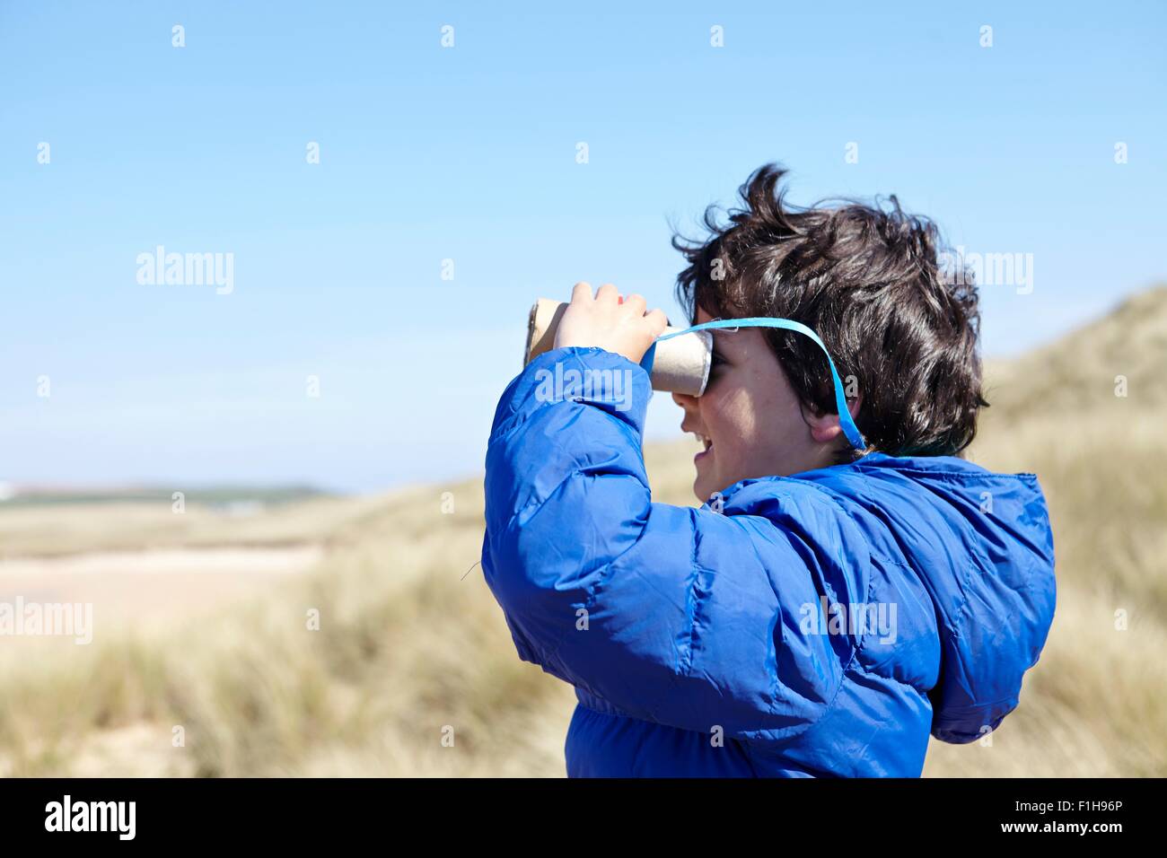 Jeune garçon sur la plage, regardant à travers les jumelles semblant Banque D'Images