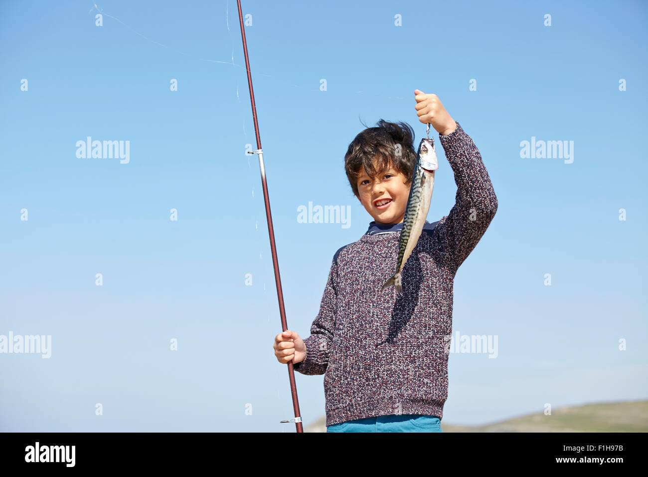 Young boy holding up canne à pêche et poissons Banque D'Images